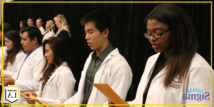 加州大学洛杉矶分校 nursing students standing in a line holding a pieces of paper reciting an oath