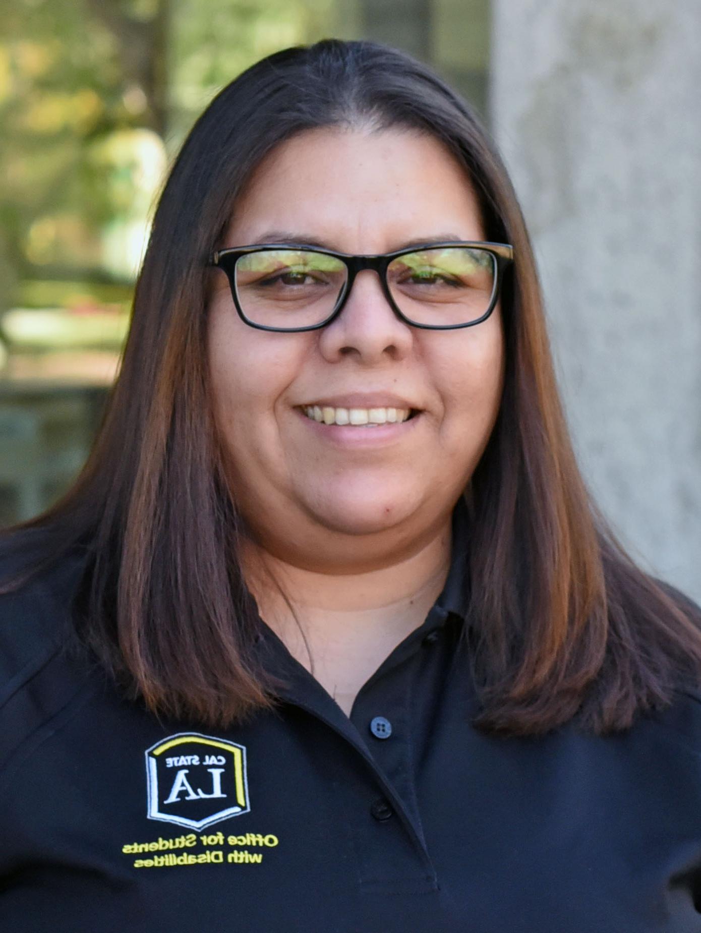 A person with should-length hair, wearing glasses and smiling.