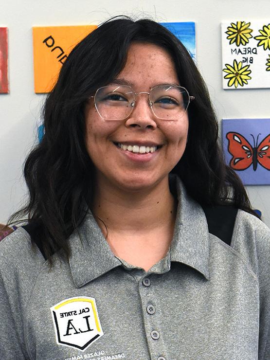 A person with medium length hair and glasses smiling