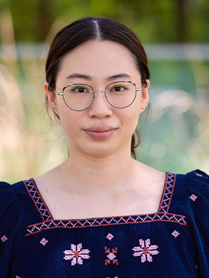 A person with glasses smiling slightly.