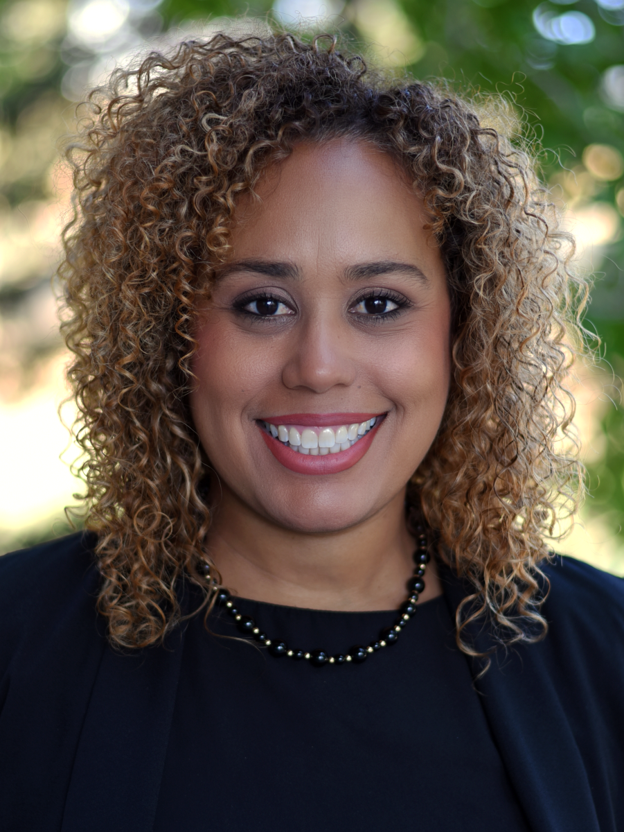 A person with shoulder-length curly hair smiling.