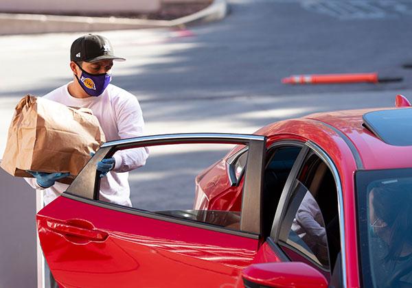 Volunteer placing food bag in the back seat of car