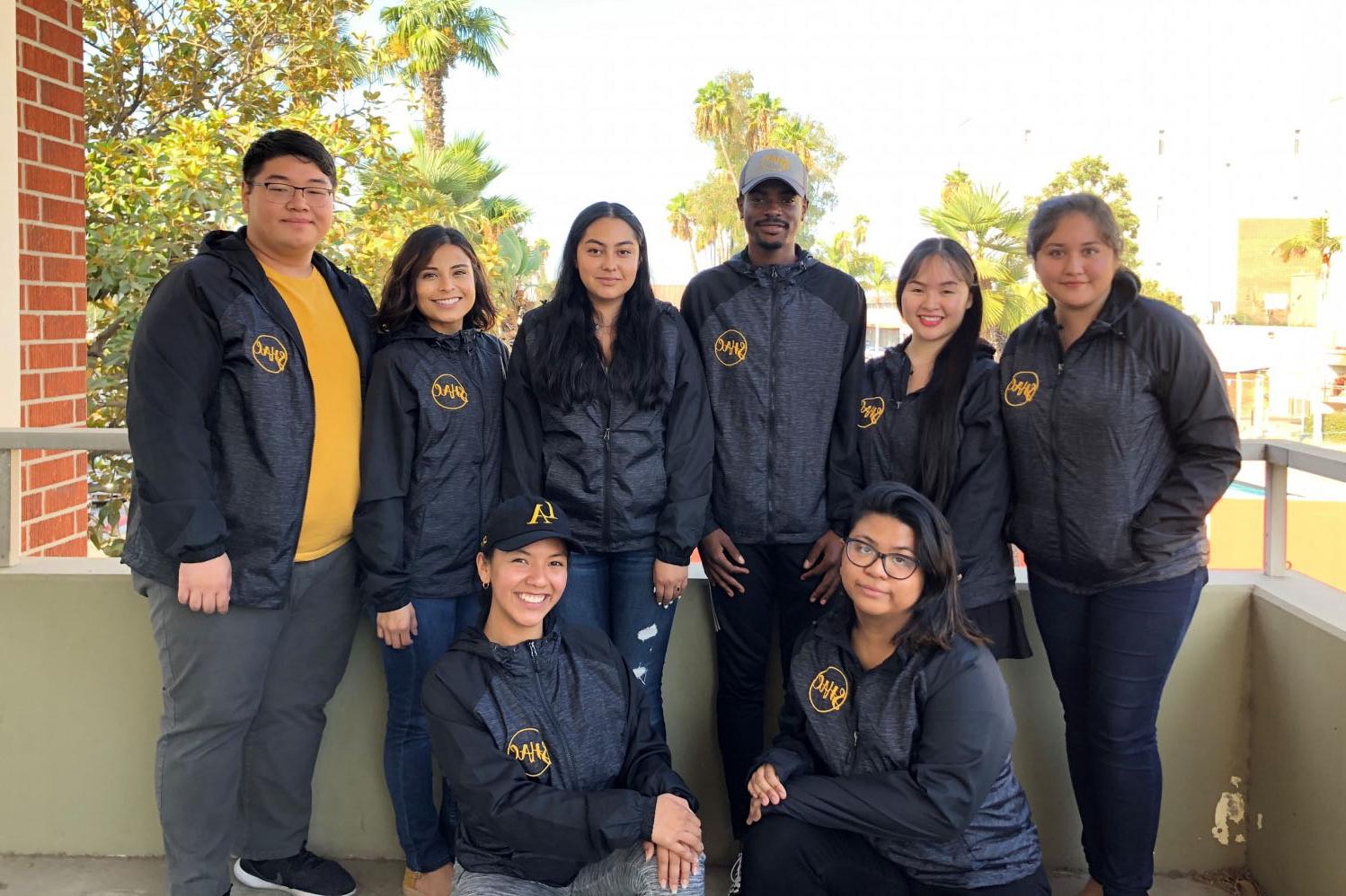 Group  of people wearing matching SHAC zip-up windbreaker jackets.