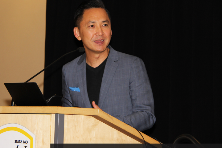 Man speaking behind a podium to an audience