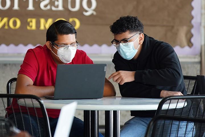 Two male students looking at a laptop at the library