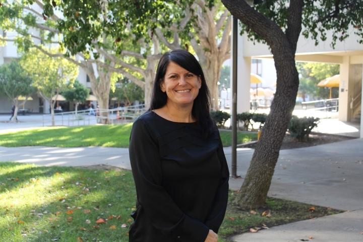 Dr. Andrea Arias standing in center of photo with grass and trees behind her