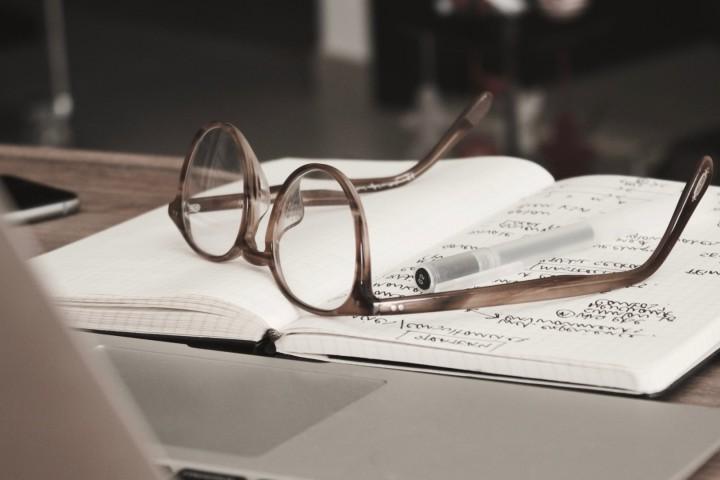 notebook with glasses resting on top